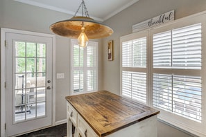 A room with a wooden table, a hanging light fixture, white shutters, and a sign that says 'thankful.'