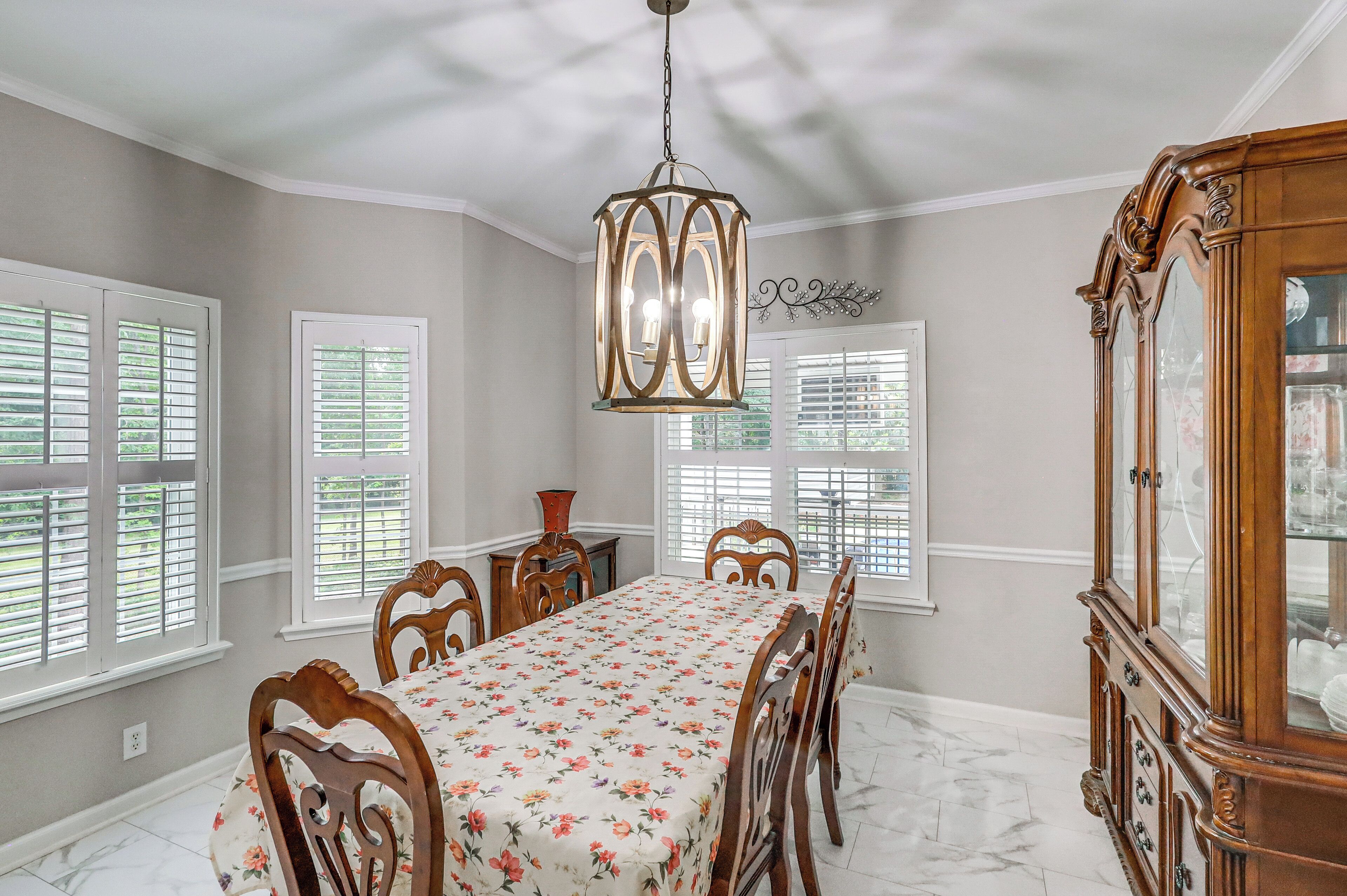 A dining room with a table set for six, a chandelier, and a wooden cabinet.