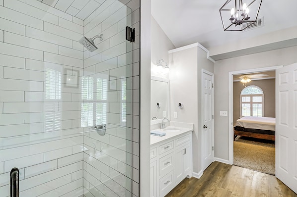 A modern bathroom with a glass shower enclosure, a white sink, and a vanity with drawers.
