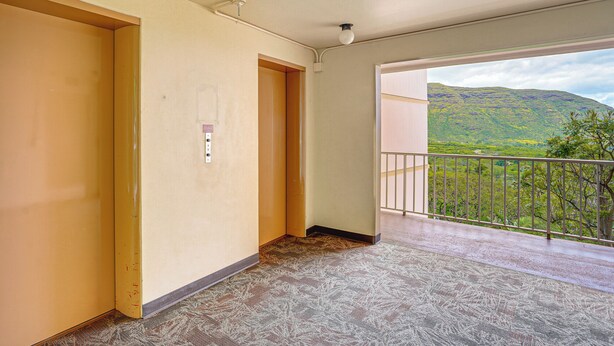 A room with a balcony, a door, and a view of a green landscape. - Pool Access, 1 Mi to Makaha Beach! Ocean-view Unit (Waianae)