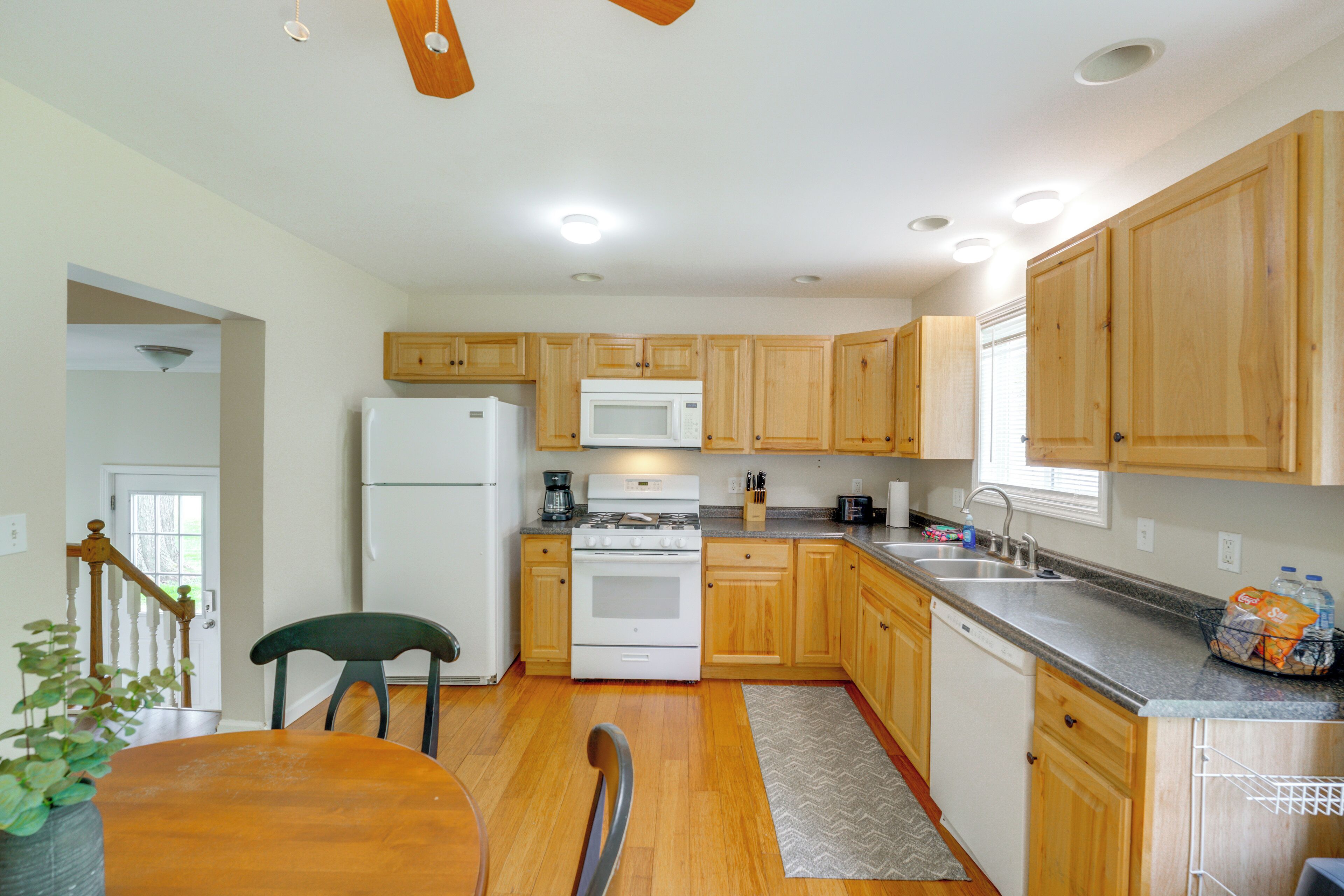 A kitchen with wooden cabinets, a refrigerator, a microwave, a stove, and a sink.