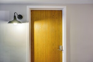 Une porte en bois avec un trou de serrure et un luminaire fixé au mur.