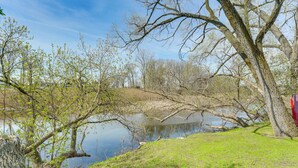 A serene lakeside scene with trees, a grassy area, and a clear sky. - Fish, Swim + Relax: Modern Condo by Lake Huron! (Port Huron)