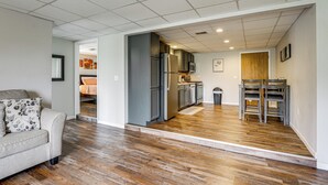 A modern apartment with hardwood flooring, a kitchenette, a dining area with chairs, and a living room with a sofa. - Fish, Swim + Relax: Modern Condo by Lake Huron! (Port Huron)