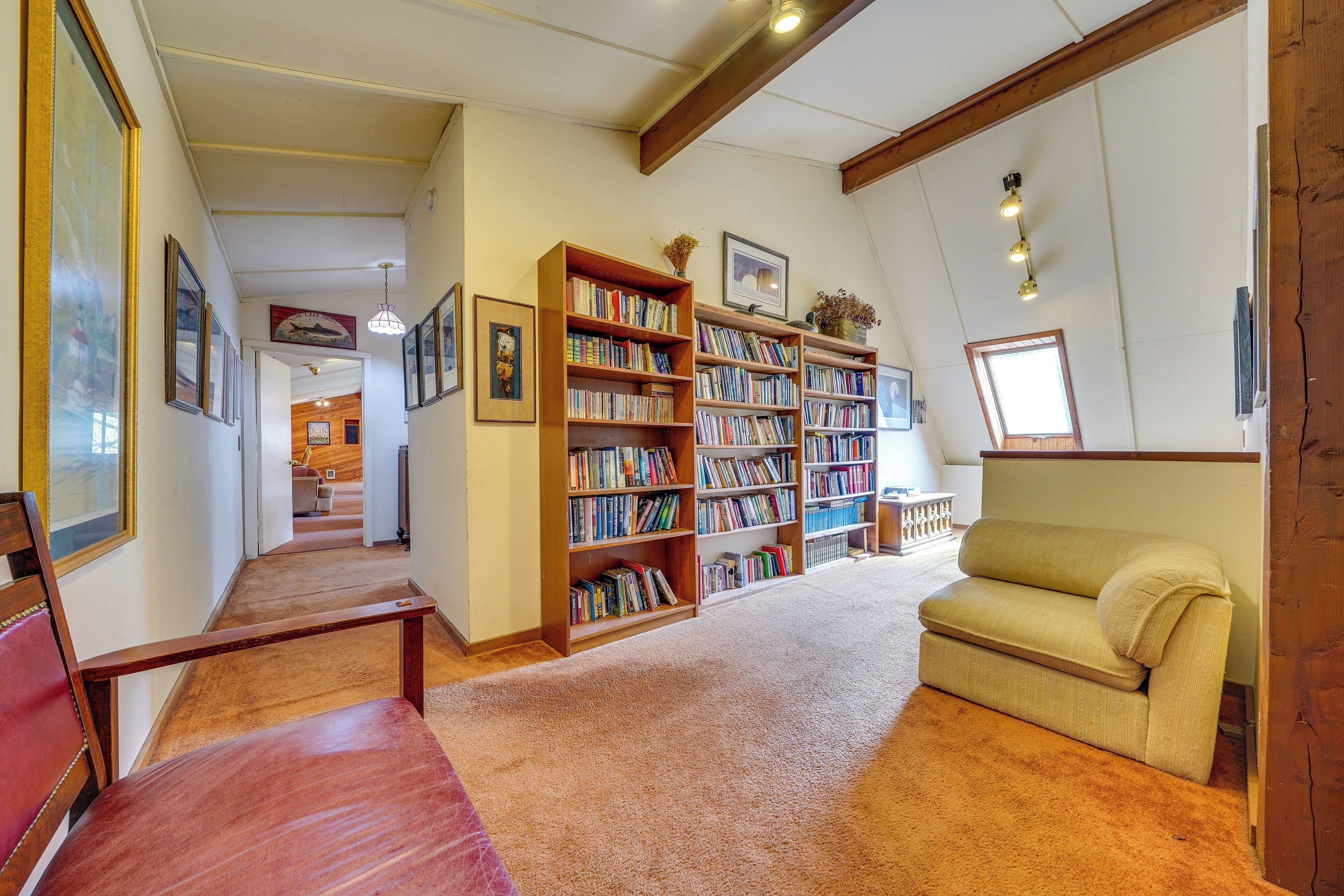 Una biblioteca con scaffali, un divano e un soffitto in legno.