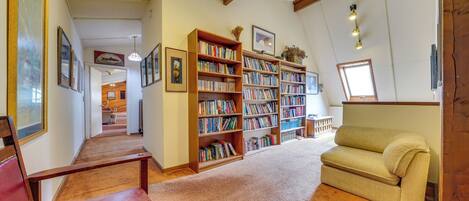 Una biblioteca con scaffali, un divano e un soffitto in legno.