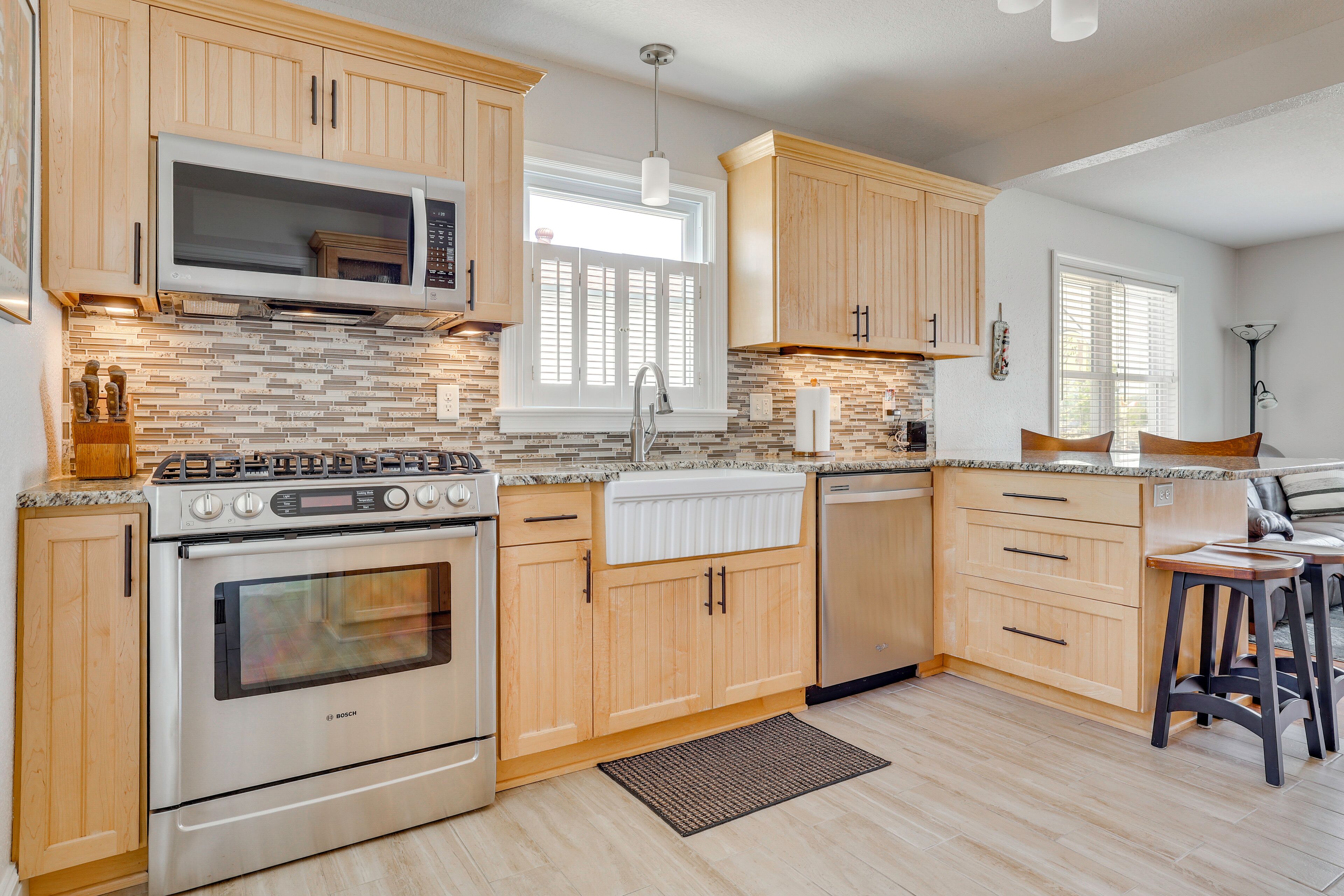 A kitchen with wooden cabinets, a Bosch oven, a microwave, and a window with blinds.