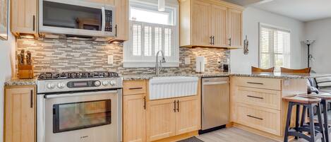 A kitchen with wooden cabinets, a Bosch oven, a microwave, and a window with blinds.