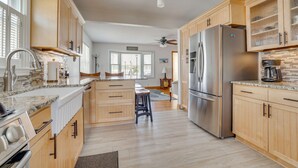 A modern kitchen with wooden cabinets, a stainless steel refrigerator, and a granite countertop.