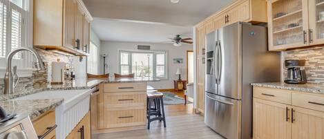 A modern kitchen with wooden cabinets, a stainless steel refrigerator, and a granite countertop.