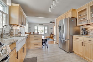 A modern kitchen with wooden cabinets, a stainless steel refrigerator, and a granite countertop.
