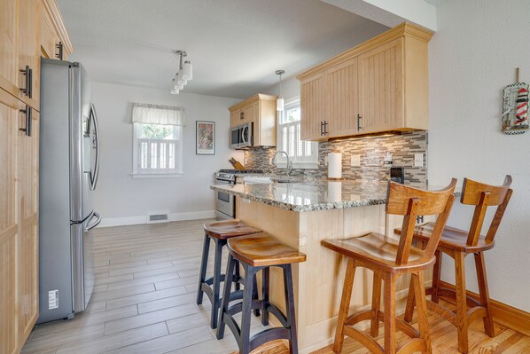 A kitchen with wooden cabinets, a granite countertop, and bar stools.