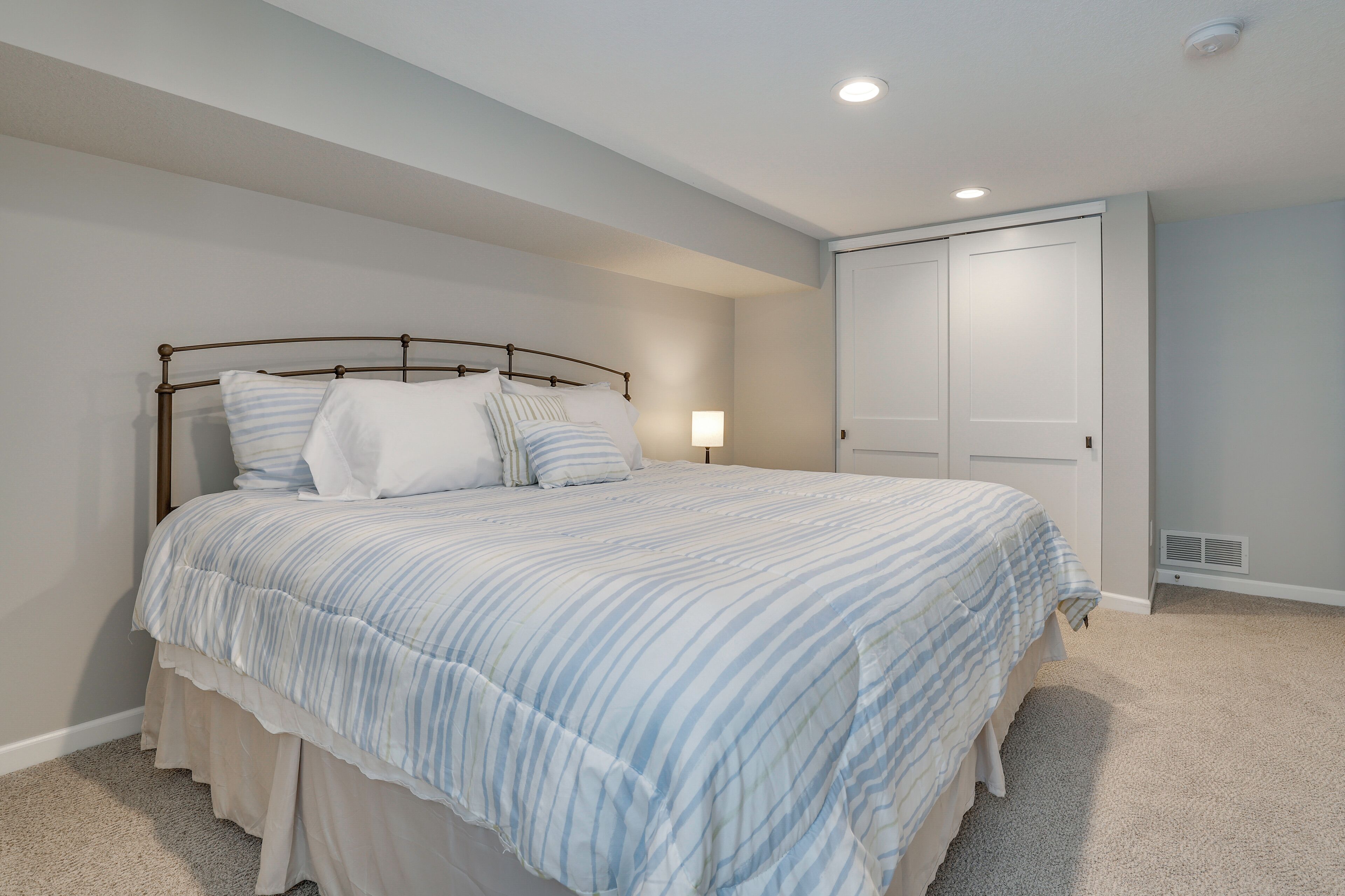 A bedroom with a bed, a nightstand, a closet, and a ceiling light.