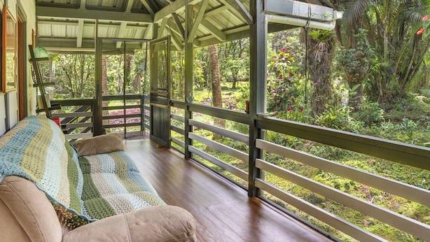 Un portico riparato con una panca di legno e una coperta all'uncinetto.