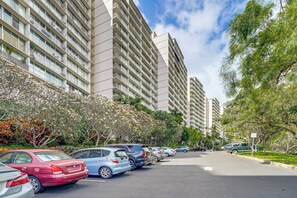 A parking lot with cars, a building with balconies, and trees. - Stay on Waianae Coast! Ocean-view Condo w/ Pools (Waianae)