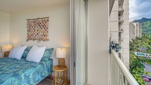 Een balkon met een bed, een wanddecoratie en uitzicht op een stadsgezicht.