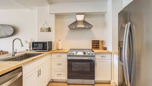 Een moderne keuken met witte kasten, roestvrijstalen apparatuur en een houten aanrecht.
