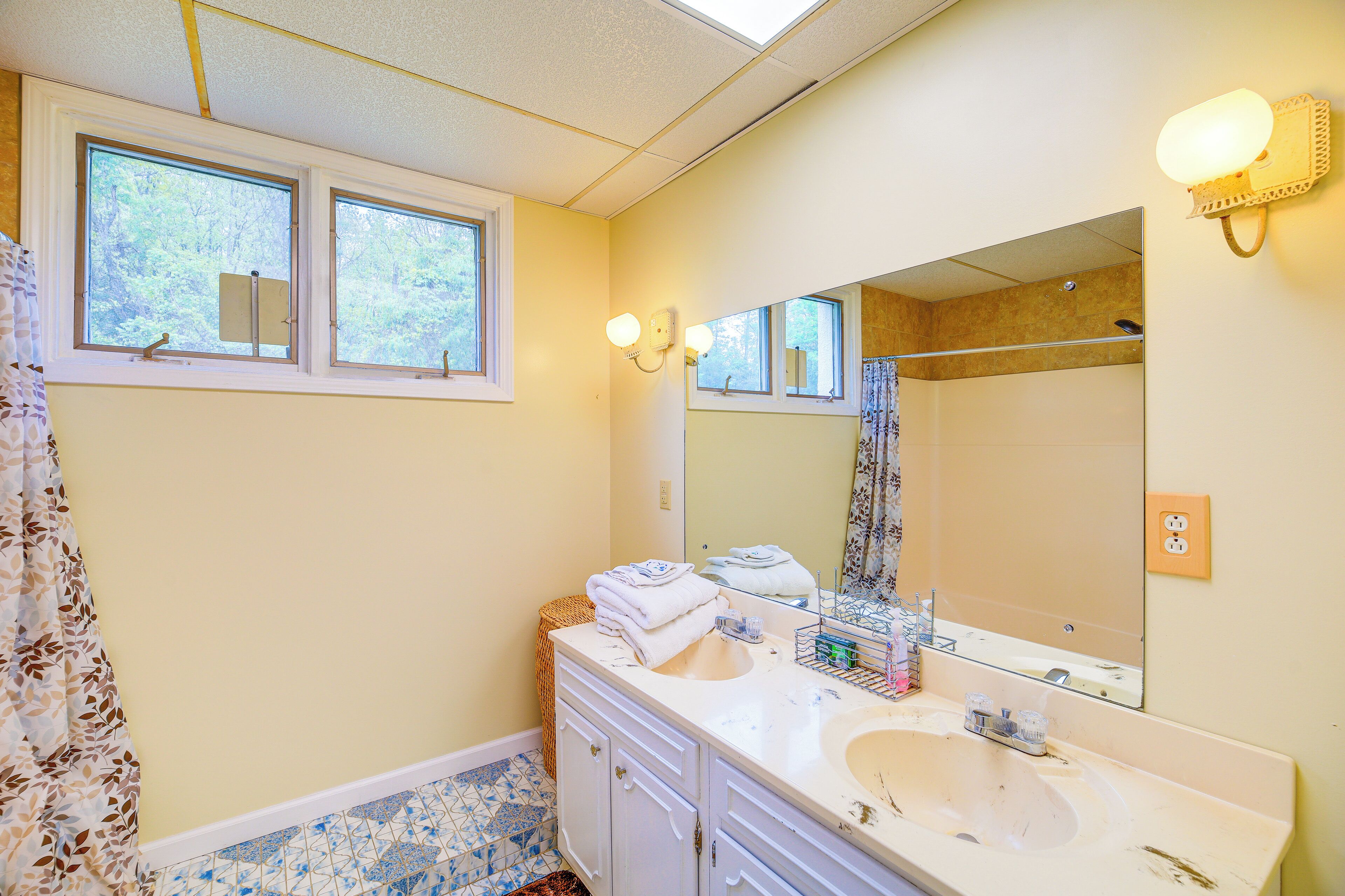 A bathroom with two sinks, a large mirror, and a shower area.
