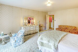 A bedroom with a bed, a chair, a dresser, and a mirror.