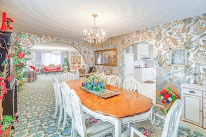 A dining area with a wooden table, white chairs, and a chandelier.