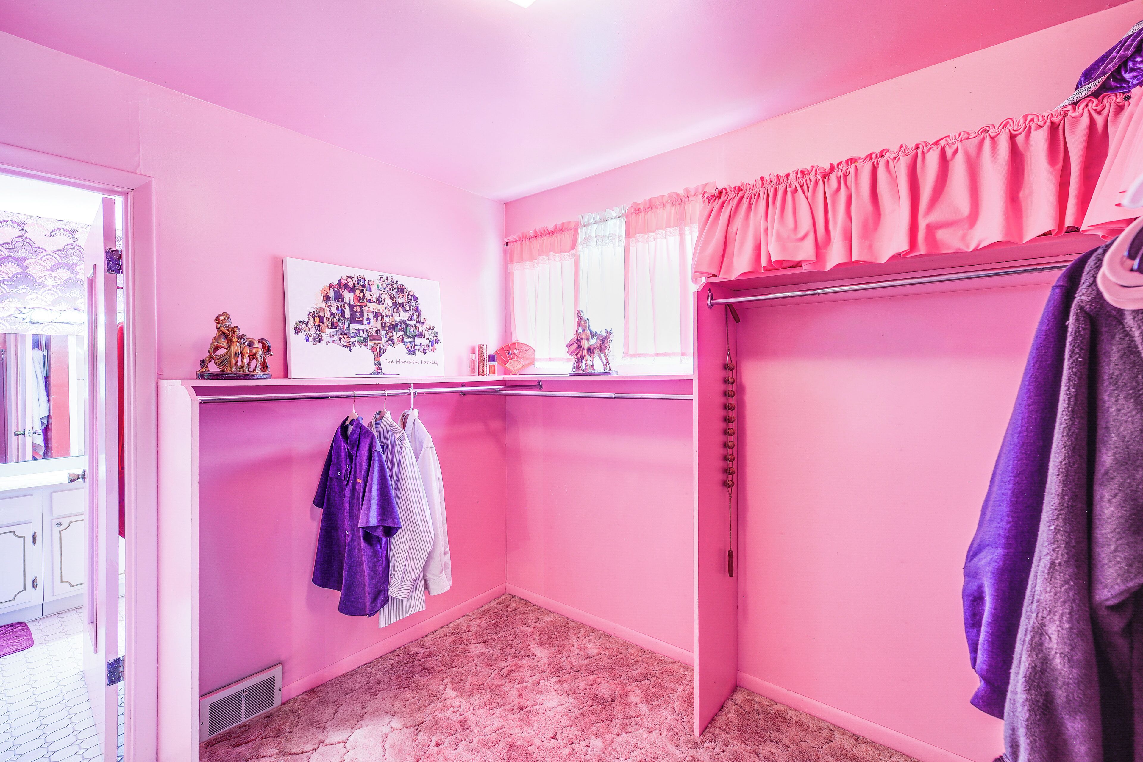 A pink room with a closet, a radiator, and a window with curtains.