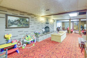 Una sala de estar con chimenea, un cuadro grande y una alfombra roja estampada.