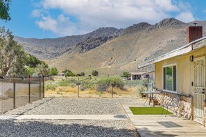 Vista de montaña con una casa, un patio cercado y un muro de piedra.