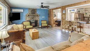 A living room with a fireplace, a television, and a dining area with wooden furniture.