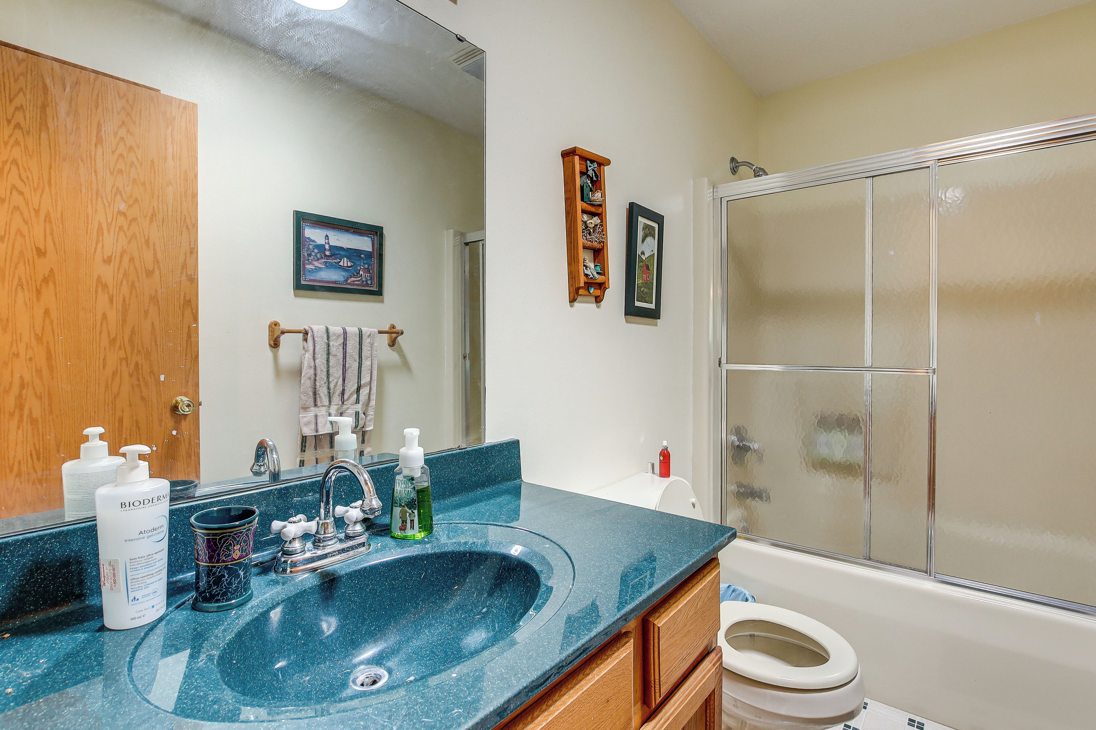 A bathroom with a sink, mirror, toilet, and shower.