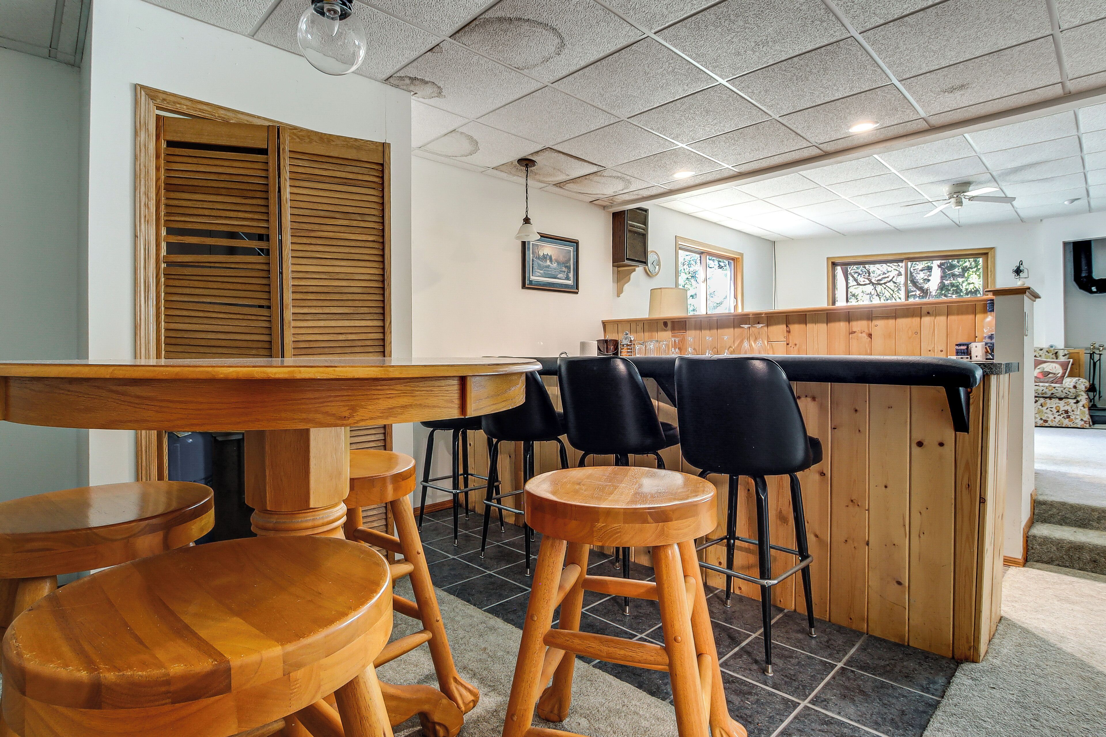 Un espace bar en bois, avec des tabourets, un comptoir et une vue sur l’extérieur.