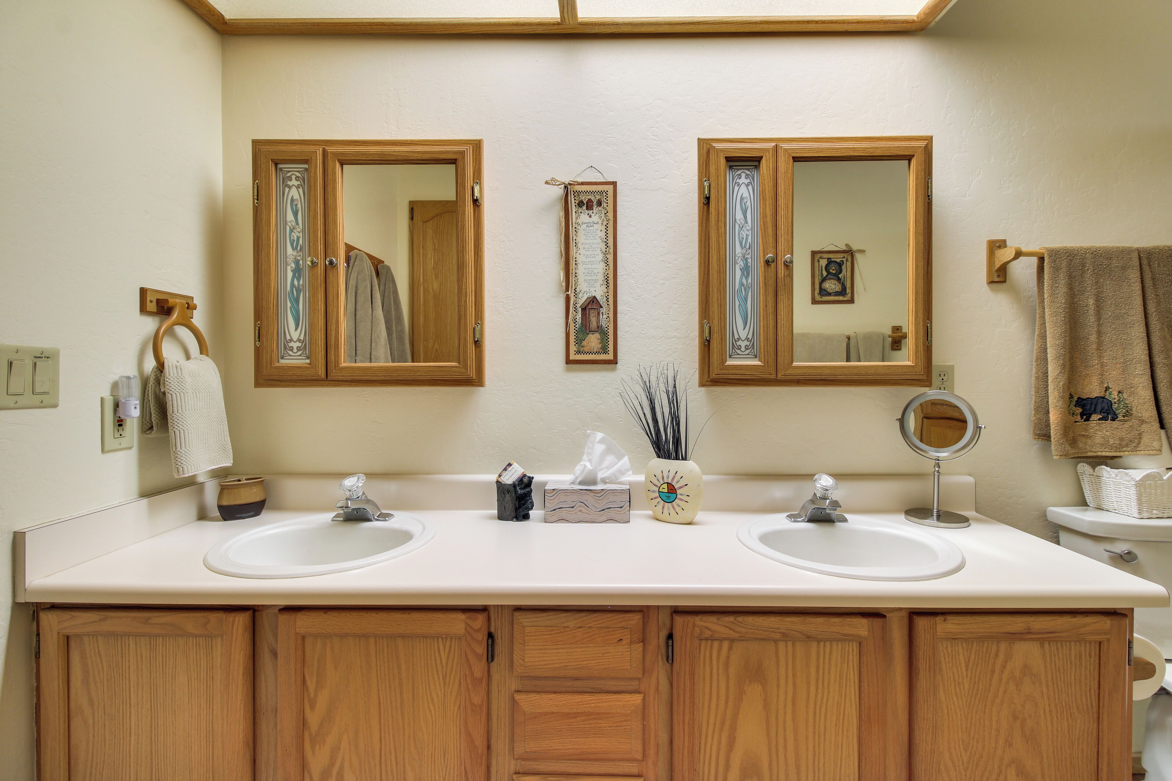 A bathroom with two sinks, wooden cabinets, and two mirrors.