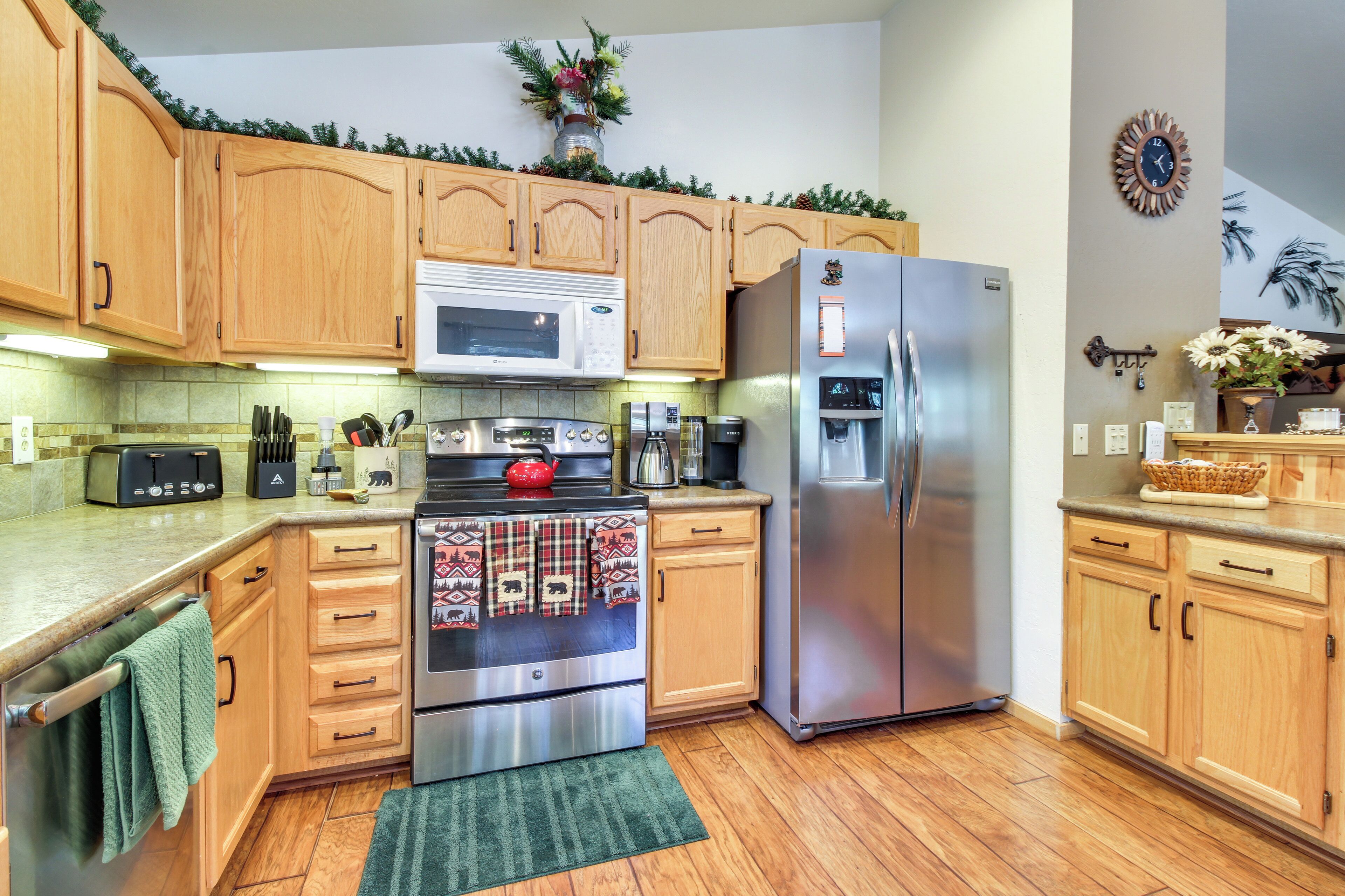 A kitchen with wooden cabinets, a stainless steel refrigerator, a microwave, and a stove.