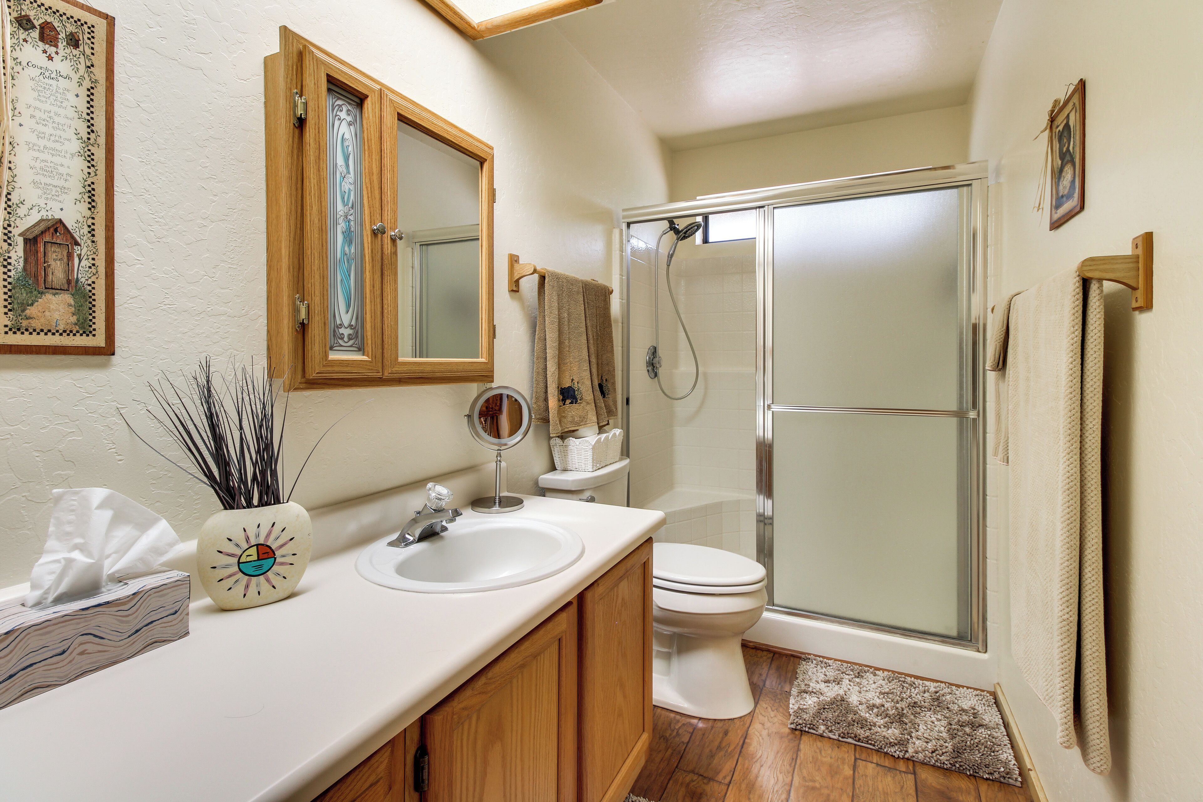 A bathroom with a wooden vanity, a sink, a toilet, and a glass-enclosed shower.