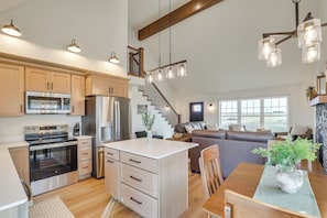 A spacious kitchen with modern appliances, a central island, and a cozy living area with a fireplace.