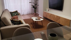 A modern living room with a sofa, a coffee table, a TV, and a potted plant. - Cangas with charm (Cangas)