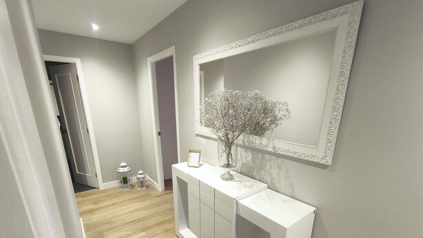 A hallway with a white console table, a mirror, and a vase with dried flowers. - Cangas with charm (Cangas)