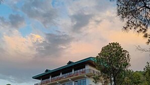 A two-story building with a balcony, surrounded by trees and a dirt path. - Lap of Himalayas Resort Kausani (Kausani)