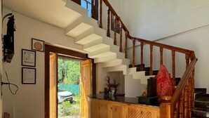 A staircase leading to an upper floor, a wooden bench, and a kitchen area with a counter. - Lap of Himalayas Resort Kausani (Kausani)