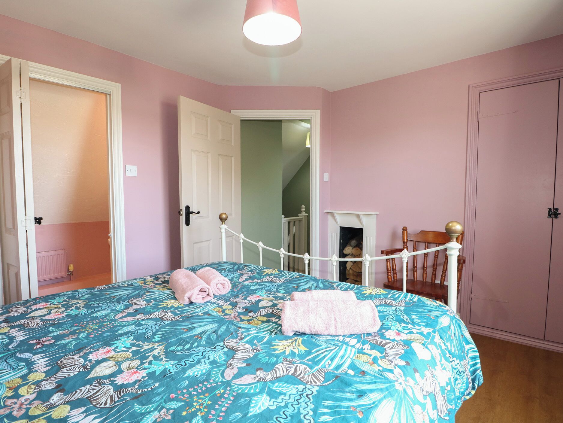 A bedroom with a bed, a door, a staircase, and a wardrobe.