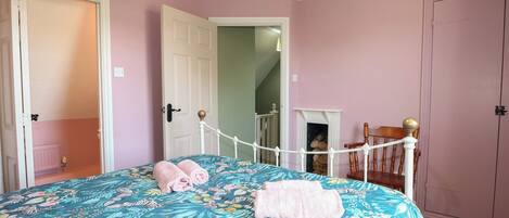 A bedroom with a bed, a door, a staircase, and a wardrobe.