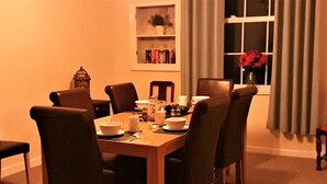 Un comedor con una mesa de madera, seis sillas y un ventanal con cortinas.