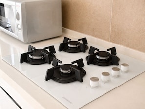 A kitchen with a white countertop, a microwave, and a gas stove with four burners and four knobs. - sandra 20 F 27 (Marsa)