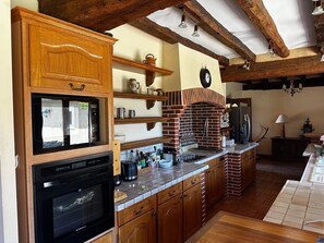 A kitchen with a built-in oven, a coffee maker, and a brick oven. - Blue Lake House (Paulnay)