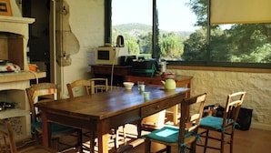 Een rustieke keuken met een houten tafel en stoelen, een magnetron en uitzicht op de omgeving.