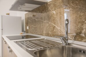A kitchen with a stainless steel sink, a modern faucet, and a marble backsplash. - Nova Suite - Apartment 100 (Calatafimi)