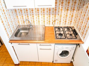 Cozinha compacta com pia, fogão e máquina de lavar.