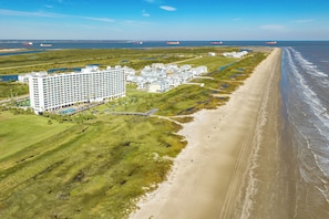 Ein Küstenhotel mit mehreren Gebäuden, einem Strand und einem Steg.