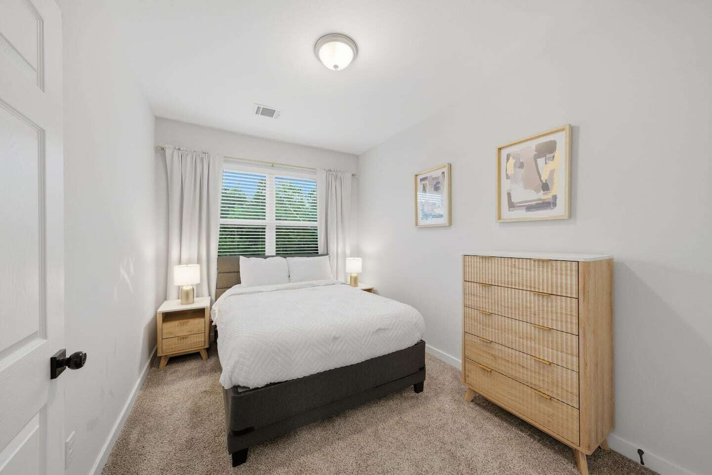 Une chambre à coucher comprenant un lit, des tables de chevet, une armoire, une fenêtre avec des rideaux et un luminaire au plafond.