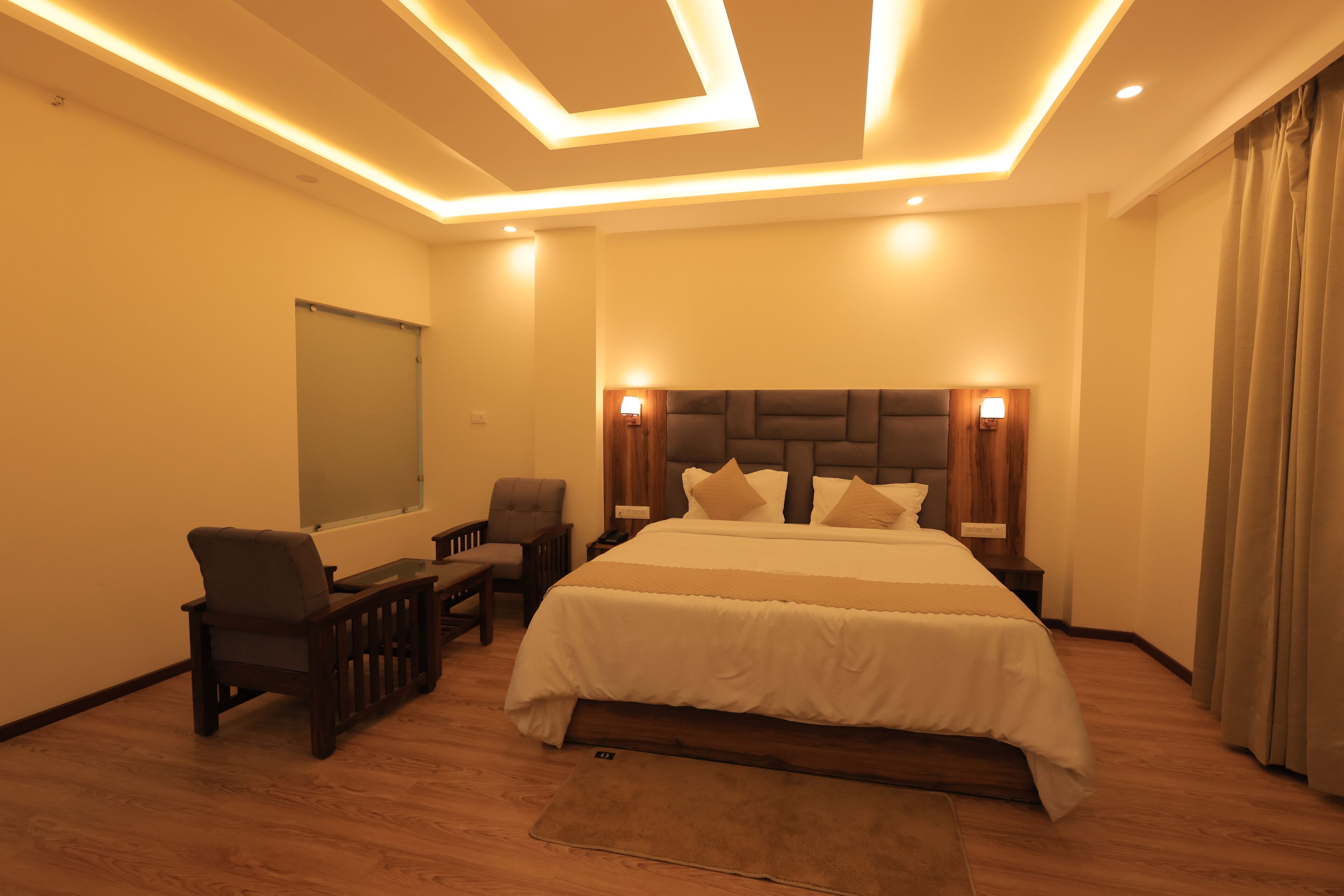 Habitación de hotel con una cama grande, dos mesitas de noche, un escritorio con silla, una ventana e iluminación empotrada en el techo.