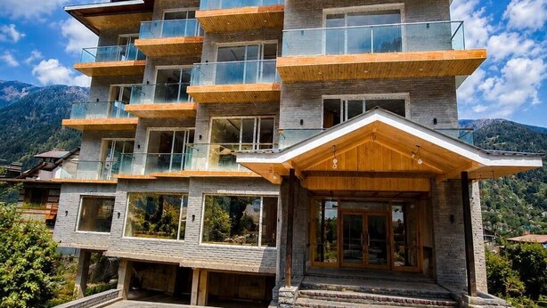 A multi-story building with balconies, large windows, and a stone facade. - Omya Mountain Retreat Manali (Manali)